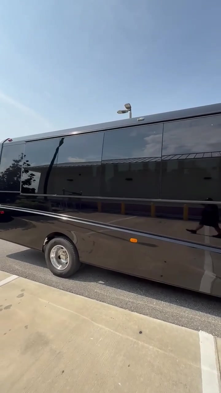 Full side view of AVPR's black 24-passenger shuttle bus