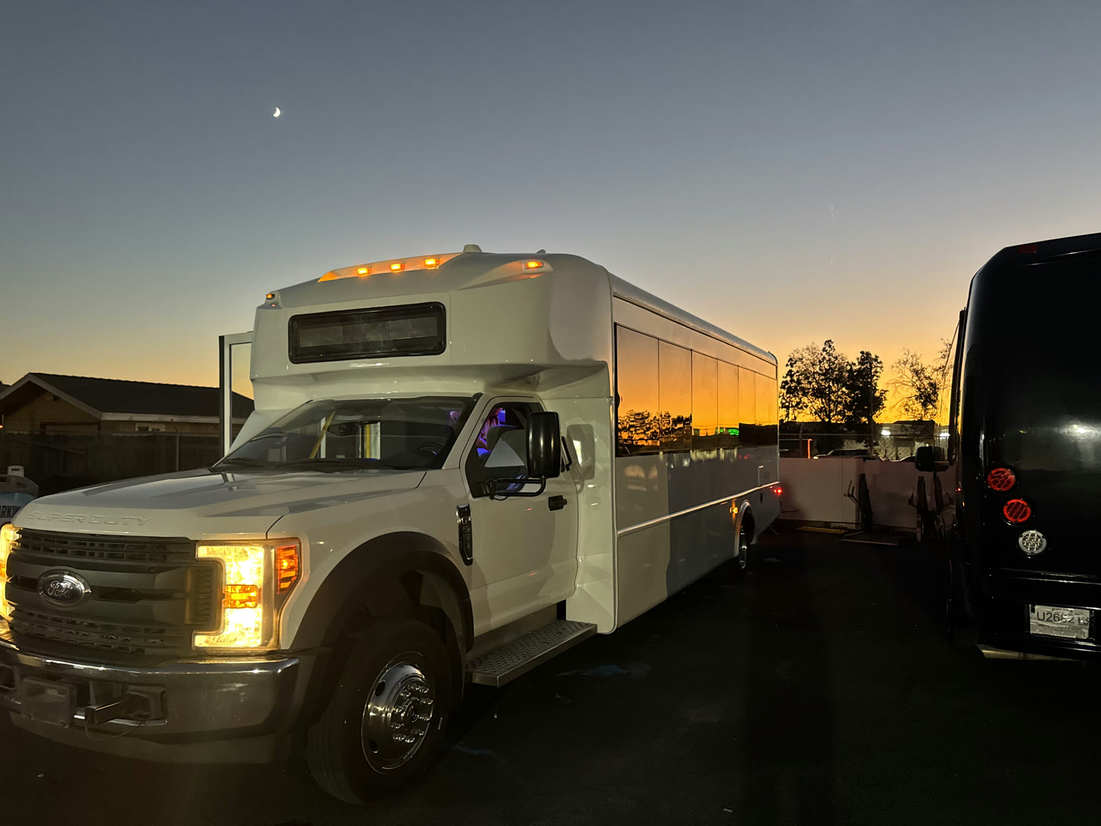 Front three-quarter view of the white Ford F-550 Party Bus at sunset