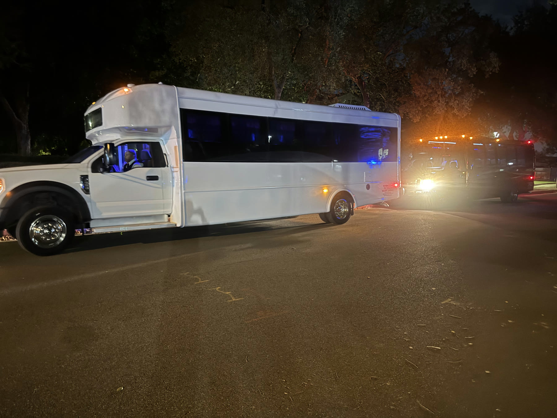 Side view of the white Party Bus parked outdoors at night