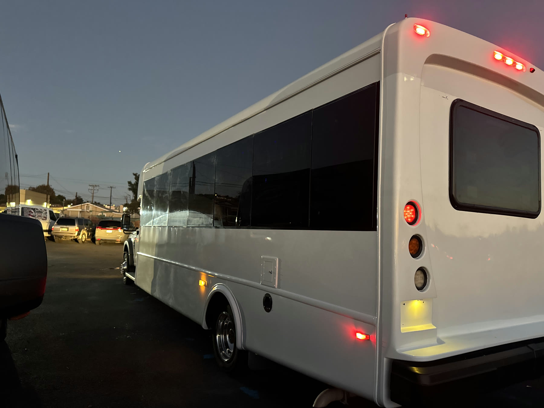 Rear three-quarter view of the white Party Bus showing its long passenger cabin